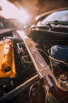 barre anti-rapprochement en aluminium fixée entre les deux tourelles d'amortisseurs sous le capot ouvert d'une voiture de sport