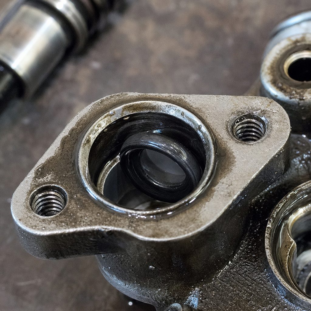 gros plan sur un joint torique noir mal positionné dans un maître-cylindre d'embrayage démonté, traces de liquide hydraulique visibles sur le corps métallique
