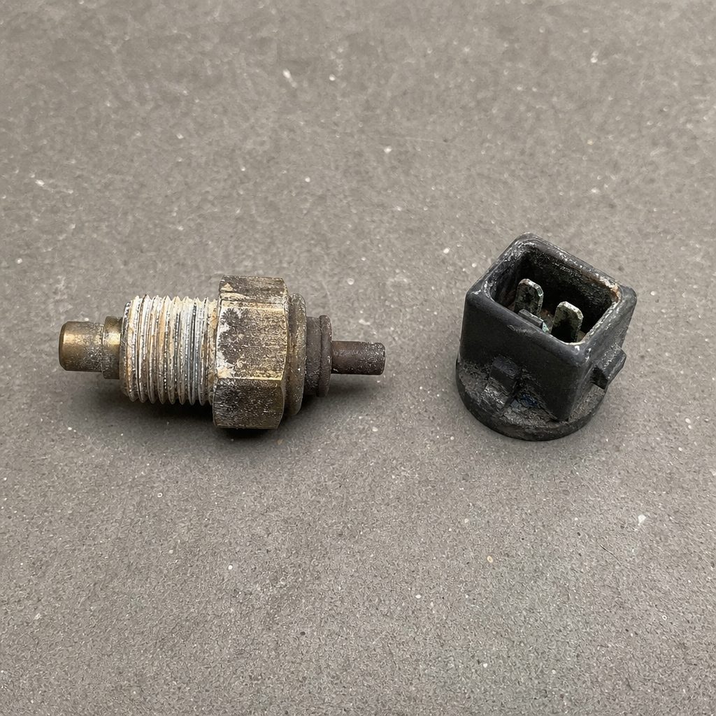 thermocontact démonté d'un radiateur automobile, connecteur électrique oxydé et traces de calcaire sur le filetage